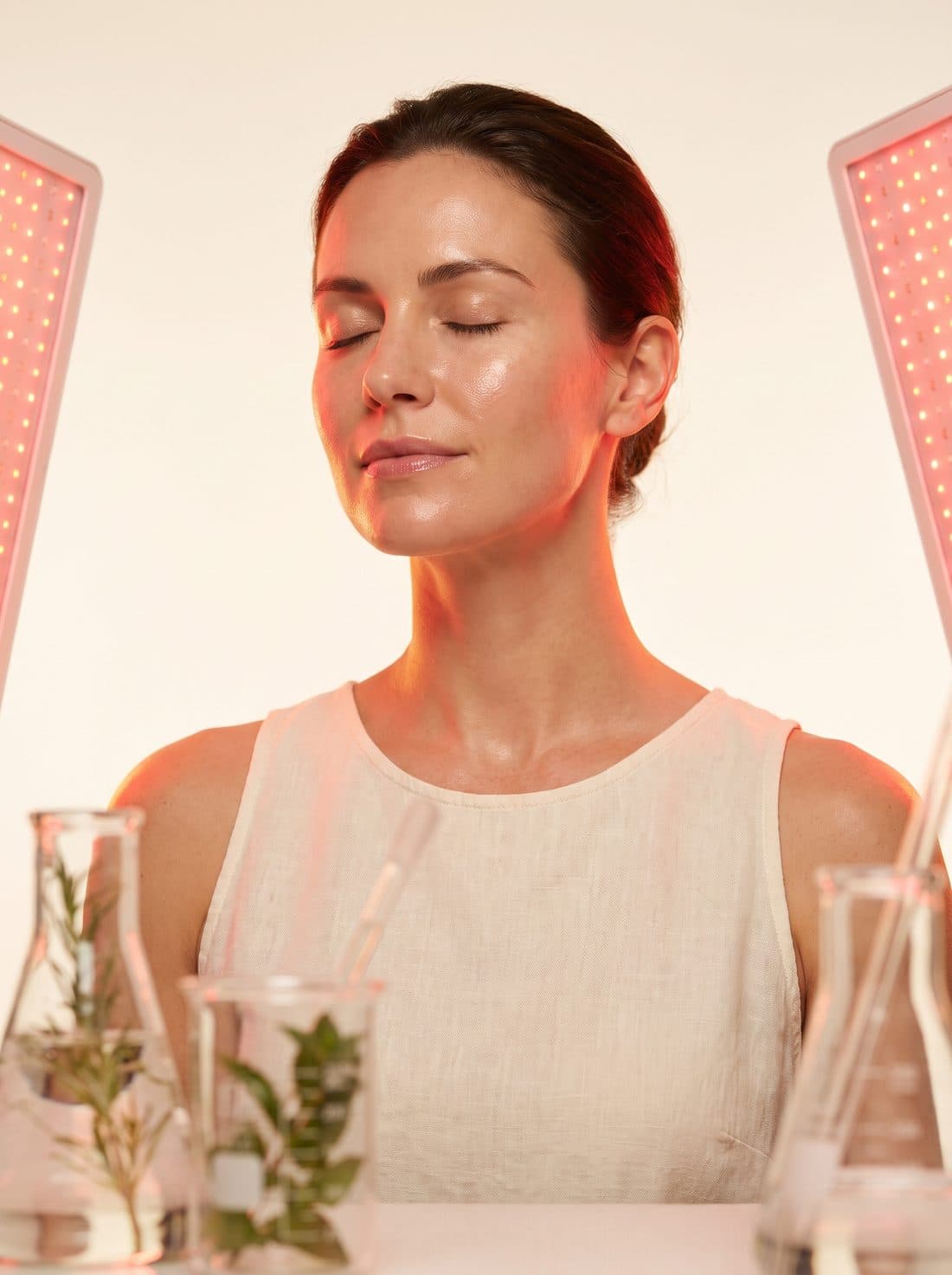 A woman with glowing skin, eyes closed, bathed in soft warm red therapeutic light